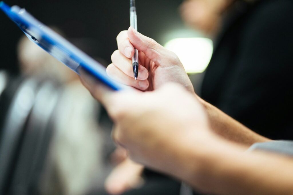 Hands holding a clipboard and pen while reviewing paperwork