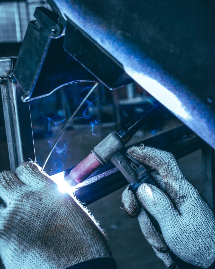 Gloved hands TIG welding a steel part